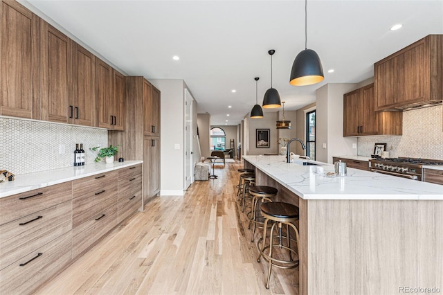 kitchen featuring decorative backsplash, a breakfast bar, stainless steel range, decorative light fixtures, and a large island