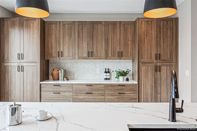 kitchen featuring tasteful backsplash, light stone counters, and sink