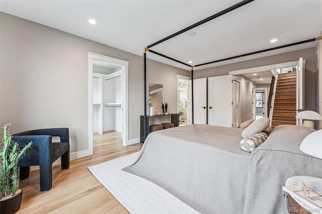 bedroom with a walk in closet, a closet, and light wood-type flooring