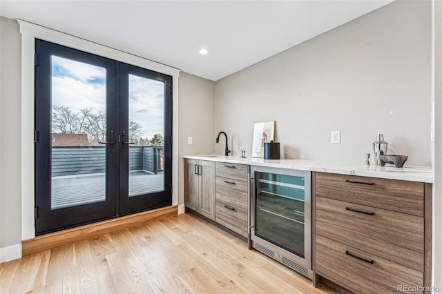 bar featuring french doors, light hardwood / wood-style floors, wine cooler, and sink