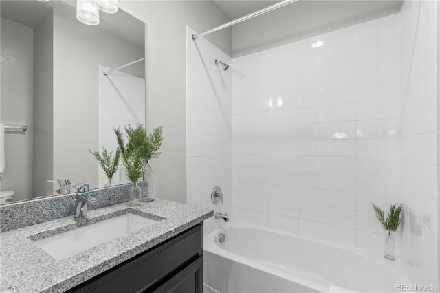 full bathroom featuring tiled shower / bath, vanity, and toilet