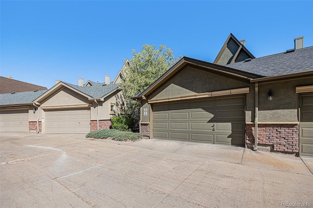 860 Bristle Pine Cir Unit A, Highlands Ranch, CO 80129 - view of property exterior with concrete driveway, stucco siding, a garage, and brick siding