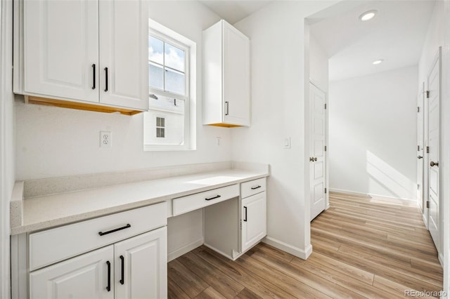 unfurnished office with baseboards, built in desk, light wood-style flooring, and recessed lighting