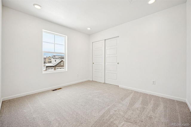 unfurnished bedroom with a closet, carpet, visible vents, and baseboards