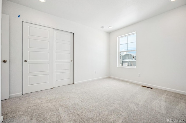 unfurnished bedroom featuring a closet, carpet flooring, visible vents, and baseboards