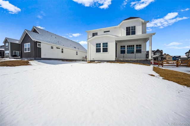 snow covered rear of property featuring a porch and board and batten siding