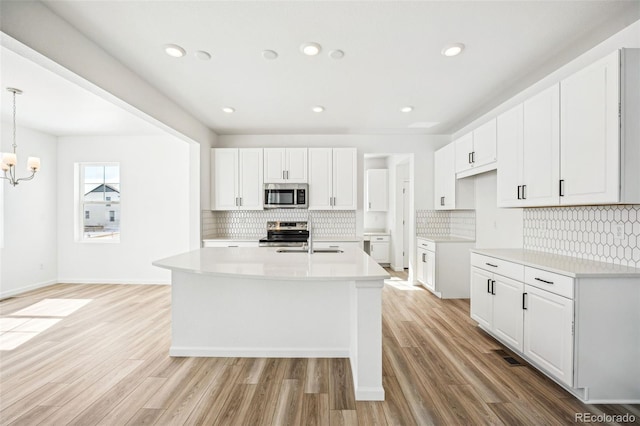 kitchen featuring stainless steel appliances, light wood-type flooring, and white cabinetry