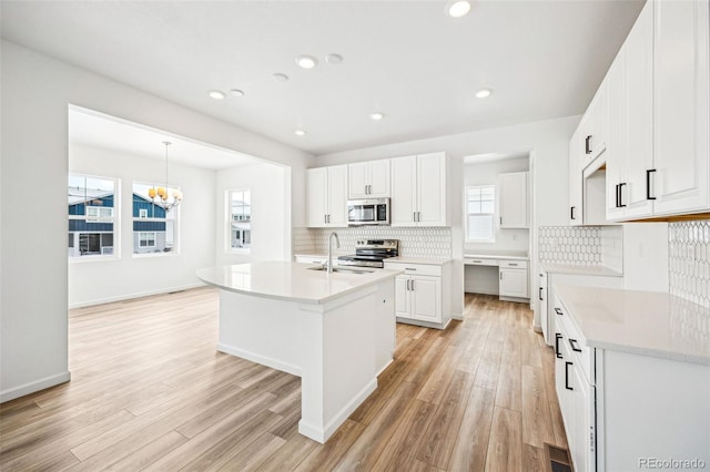 kitchen with light wood-style floors, stainless steel appliances, a sink, and light countertops