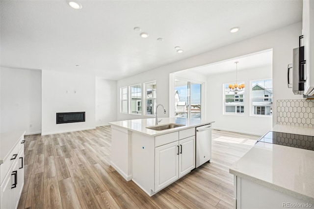 kitchen featuring light wood-type flooring, a glass covered fireplace, dishwasher, and a sink