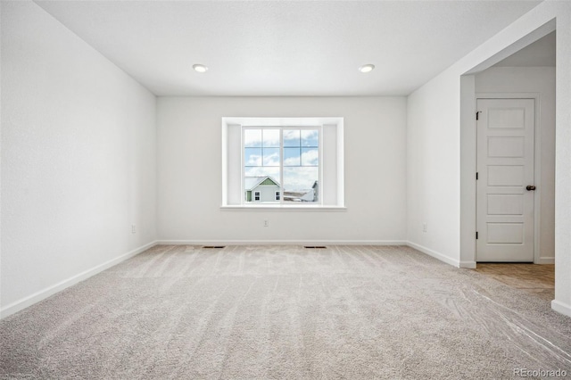 spare room featuring carpet floors, visible vents, and baseboards