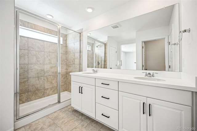 bathroom featuring visible vents, a sink, a shower stall, and double vanity