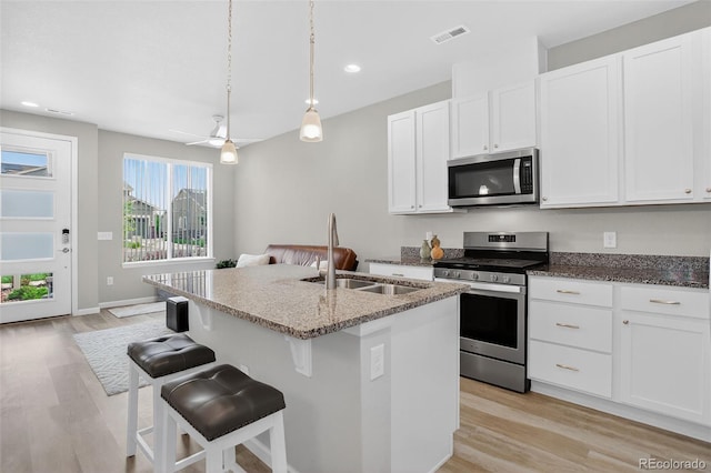 19629 W 93rd Dr Unit C, Arvada, CO 80007 - kitchen featuring appliances with stainless steel finishes, stone countertops, light wood-type flooring, a center island with sink, and white cabinetry