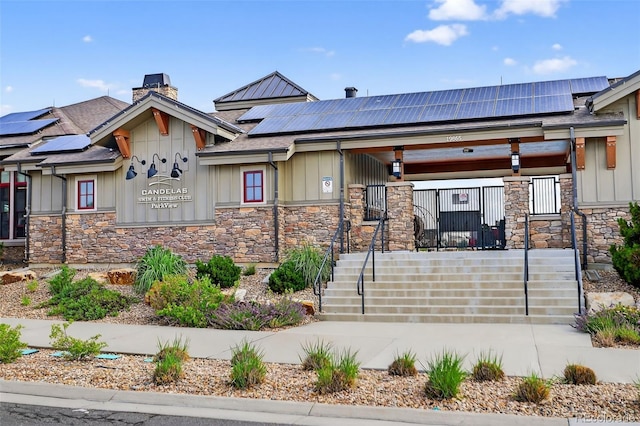 19629 W 93rd Dr Unit C, Arvada, CO 80007 - view of front of house with stone siding, roof mounted solar panels, a porch, and board and batten siding