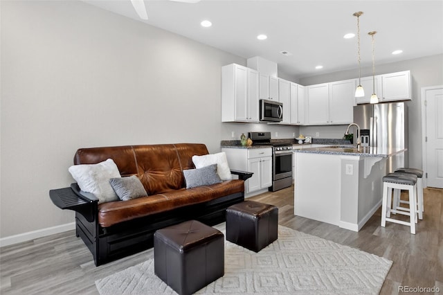 19629 W 93rd Dr Unit C, Arvada, CO 80007 - kitchen with stainless steel appliances, open floor plan, light wood finished floors, a kitchen breakfast bar, and white cabinetry