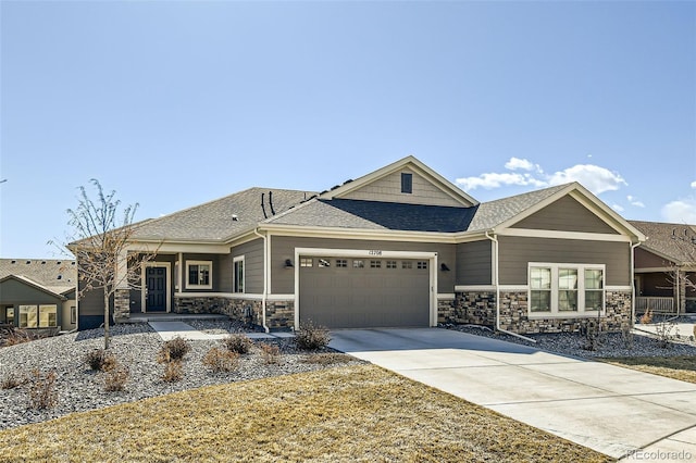 view of front of home featuring a shingled roof, stone siding, an attached garage, and concrete driveway