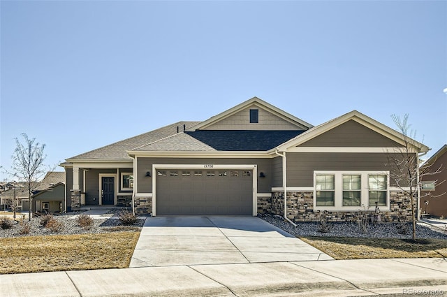 view of front facade with a shingled roof, stone siding, driveway, and an attached garage