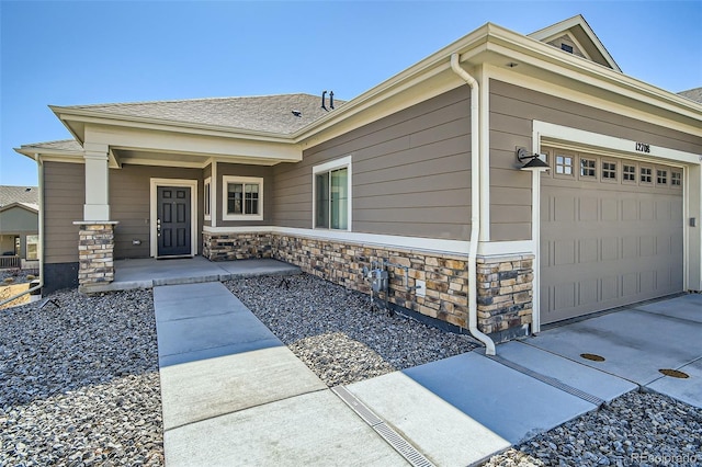 view of front of property with covered porch, stone siding, and a garage