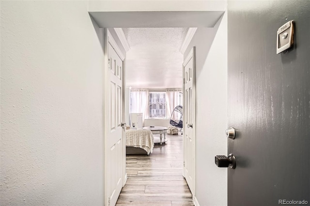 hallway featuring a textured ceiling, baseboards, and wood finished floors