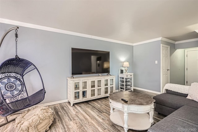 living area featuring baseboards, wood finished floors, and crown molding