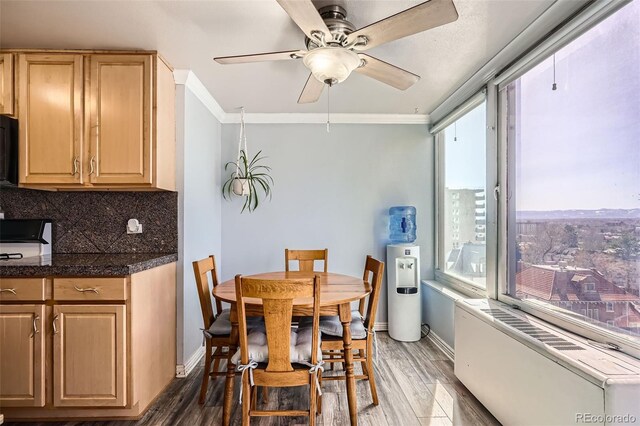 dining space with baseboards, dark wood finished floors, radiator heating unit, ornamental molding, and a ceiling fan