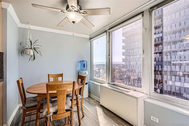 dining area featuring wood finished floors, a ceiling fan, baseboards, and ornamental molding