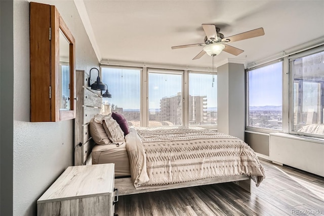 bedroom with a ceiling fan, crown molding, a city view, and wood finished floors