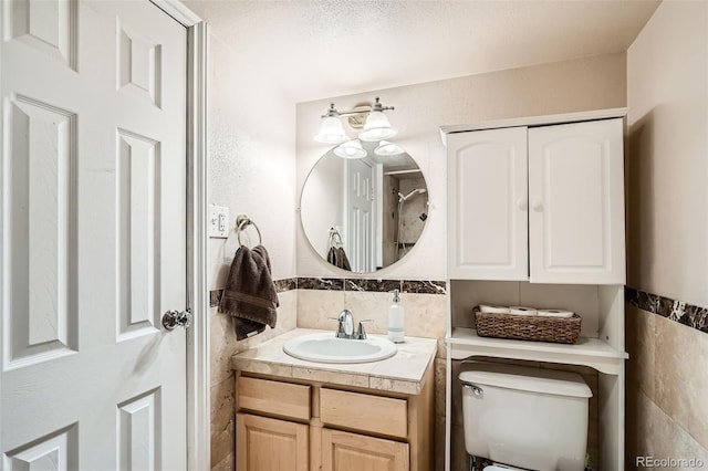 bathroom with wainscoting, toilet, tile walls, and vanity