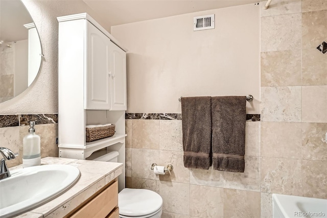 full bath featuring visible vents, a tub to relax in, toilet, and tile walls