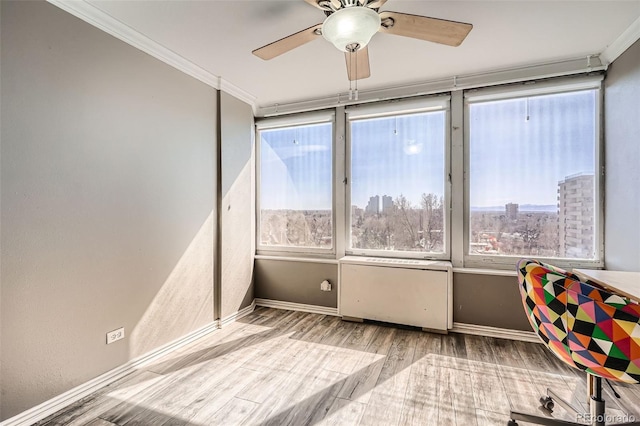 interior space featuring baseboards, ornamental molding, wood finished floors, a view of city, and a ceiling fan