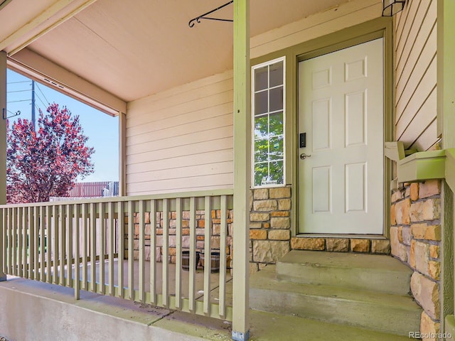 view of exterior entry with stone siding and a porch