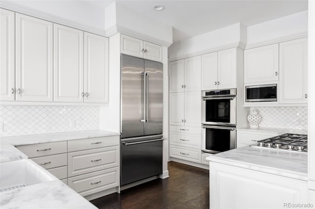 kitchen featuring light stone counters, white cabinets, dark hardwood / wood-style floors, and built in appliances