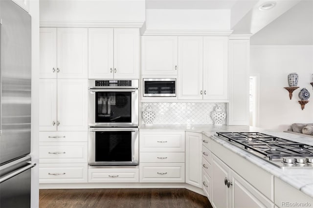 kitchen featuring white cabinetry, dark hardwood / wood-style flooring, built in appliances, decorative backsplash, and light stone counters