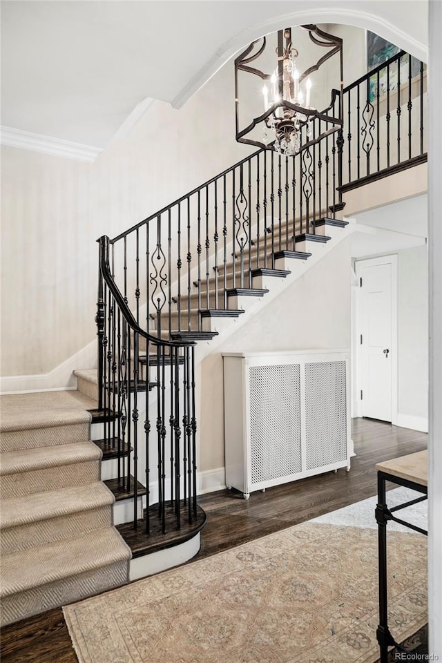 stairway with hardwood / wood-style floors, a chandelier, and ornamental molding