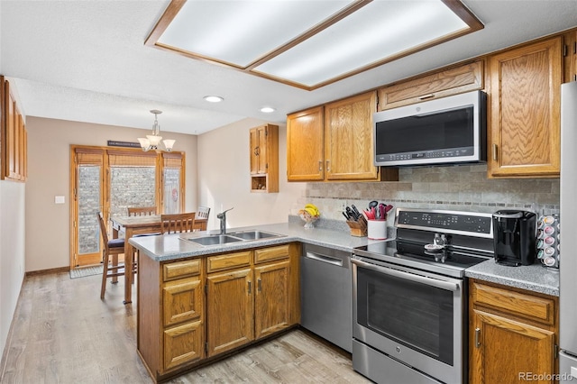 7624 S Cove Cir, Centennial, CO 80122 - kitchen with appliances with stainless steel finishes, a peninsula, light wood finished floors, tasteful backsplash, and recessed lighting