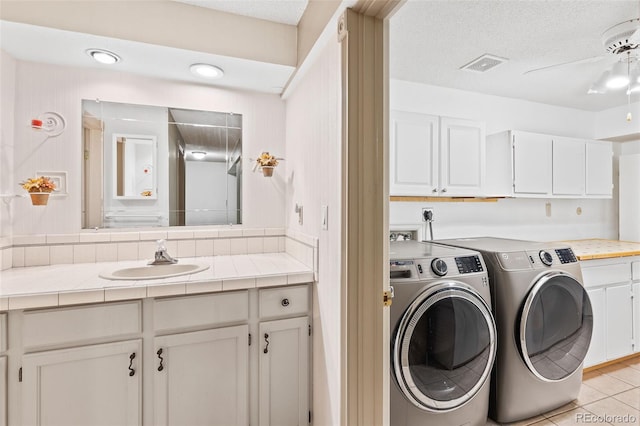 7624 S Cove Cir, Centennial, CO 80122 - laundry area featuring washing machine and clothes dryer, cabinet space, light tile patterned floors, a textured ceiling, and a ceiling fan