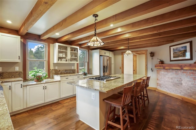 688 Obsidian Dr, Florissant, CO 80816 - kitchen with appliances with stainless steel finishes, white cabinetry, light stone counters, glass insert cabinets, and beamed ceiling