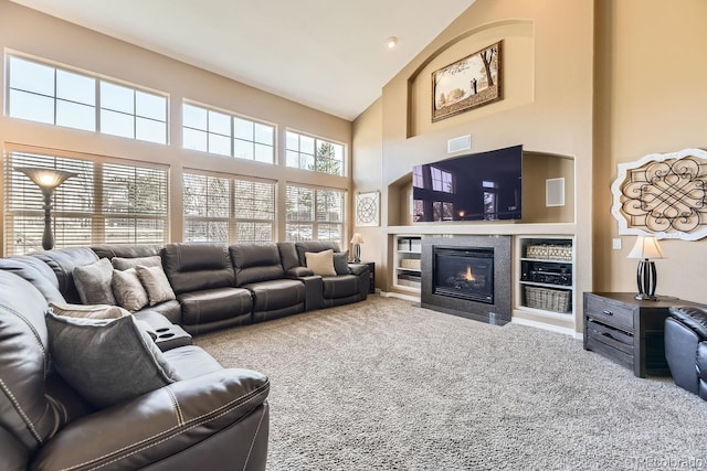 living area featuring a towering ceiling, a fireplace with flush hearth, and carpet flooring