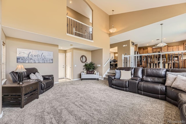 living room featuring a towering ceiling, baseboards, stairway, and light colored carpet