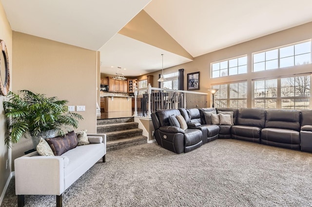 carpeted living room with stairs and high vaulted ceiling