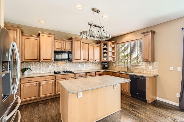 kitchen with glass insert cabinets, a sink, a center island, black appliances, and decorative light fixtures