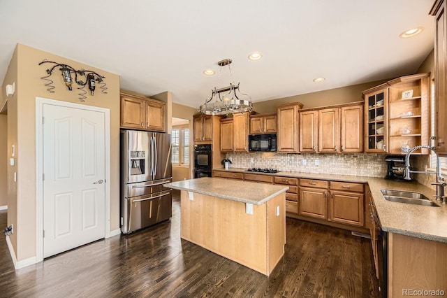 kitchen featuring a center island, hanging light fixtures, glass insert cabinets, a sink, and black appliances