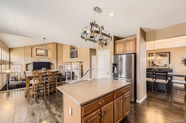 kitchen featuring a kitchen island, open floor plan, light countertops, stainless steel fridge, and decorative light fixtures