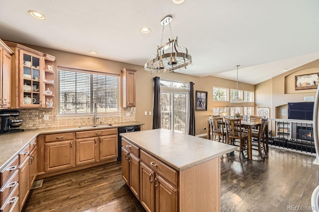 kitchen with light countertops, glass insert cabinets, a kitchen island, a sink, and dishwasher