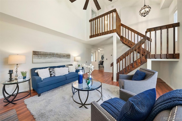 living room featuring ceiling fan with notable chandelier, a towering ceiling, and hardwood / wood-style flooring