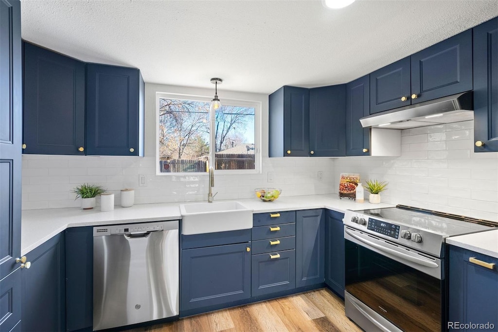 kitchen featuring decorative light fixtures, blue cabinets, sink, and stainless steel appliances