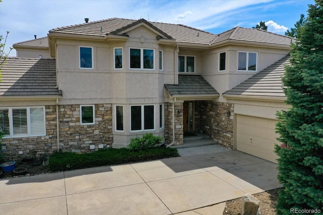 view of front of home with stone siding, concrete driveway, stucco siding, a tiled roof, and an attached garage
