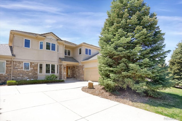 view of front of home featuring stone siding, a tile roof, an attached garage, and driveway