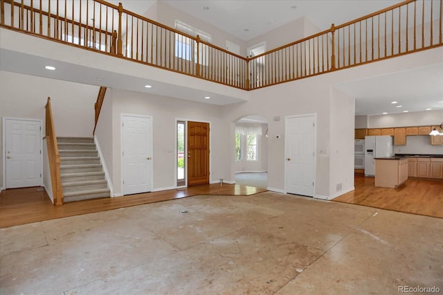 entrance foyer with a high ceiling, arched walkways, baseboards, and stairway