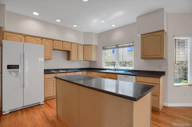 kitchen with white appliances, light brown cabinetry, dark countertops, light wood-style flooring, and a sink