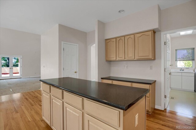 kitchen featuring light brown cabinetry, dark countertops, light wood-style flooring, french doors, and a kitchen island